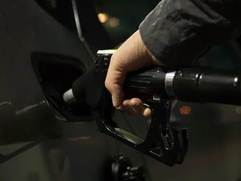 A hand holding a refuelling nozzle at a vehicle