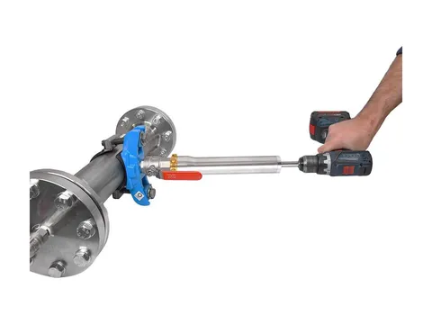 A hot tapping drilling device driven by a cordless drill, fitted through a ball valve and saddle clamp on a flanged pipe