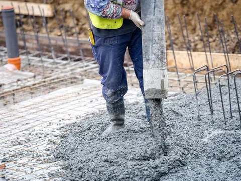 A worker pouring concrete over steel reinforcement